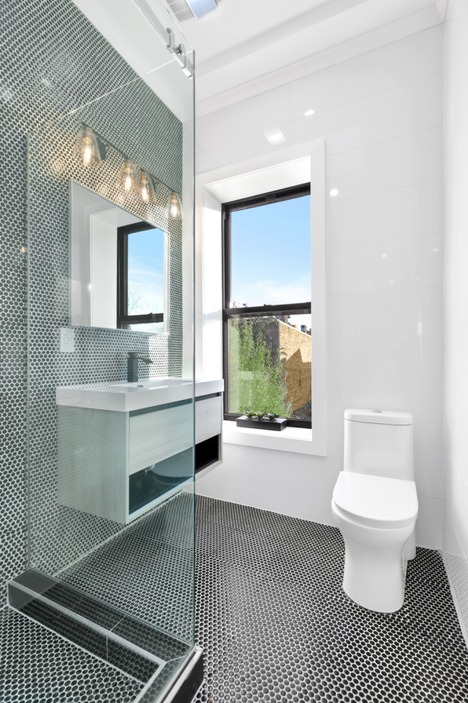 Large midcentury master bathroom in New York with flat-panel cabinets, white cabinets, an open shower, a one-piece toilet, black and white tile, mosaic tile, white walls, porcelain floors, an integrated sink, marble benchtops, grey floor, a sliding shower screen, black benchtops, a double vanity and a freestanding vanity.