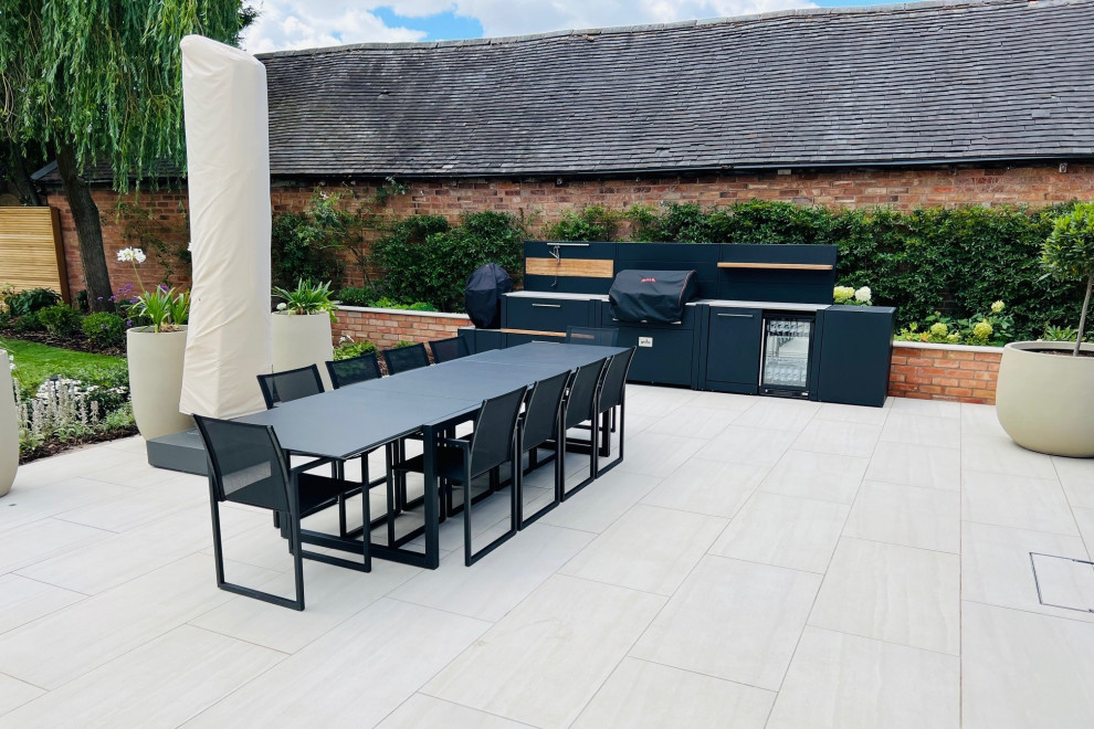 Inspiration for a medium sized contemporary back patio in West Midlands with an outdoor kitchen, natural stone paving and no cover.