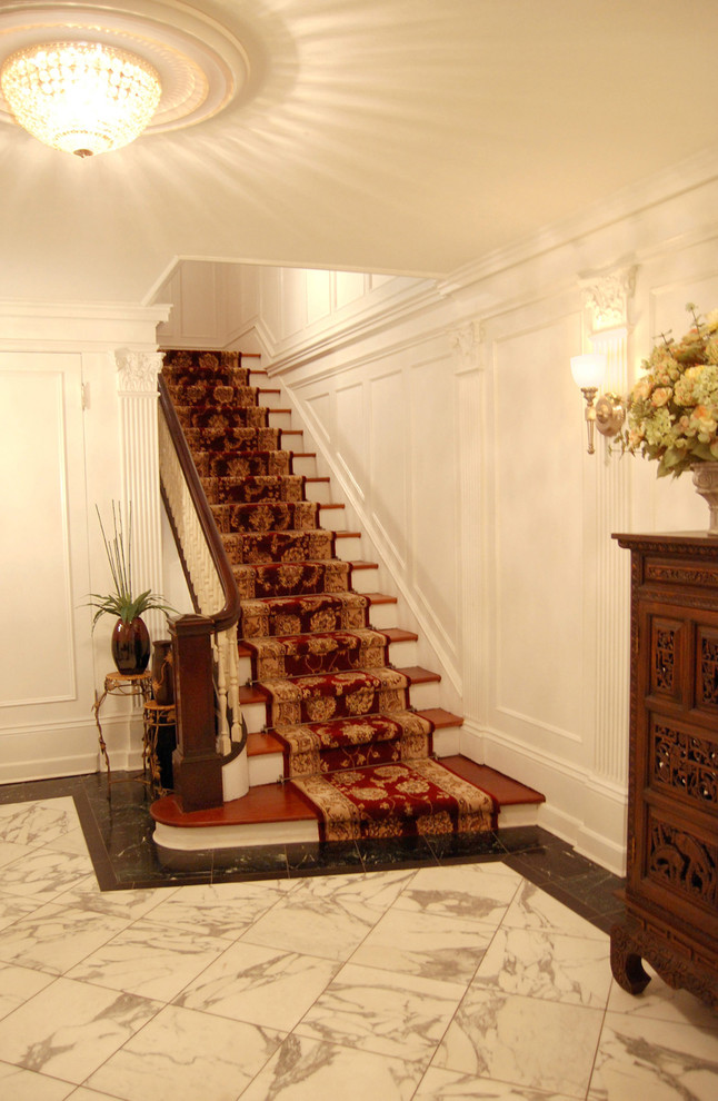 Large traditional foyer in New York with white walls and marble floors.