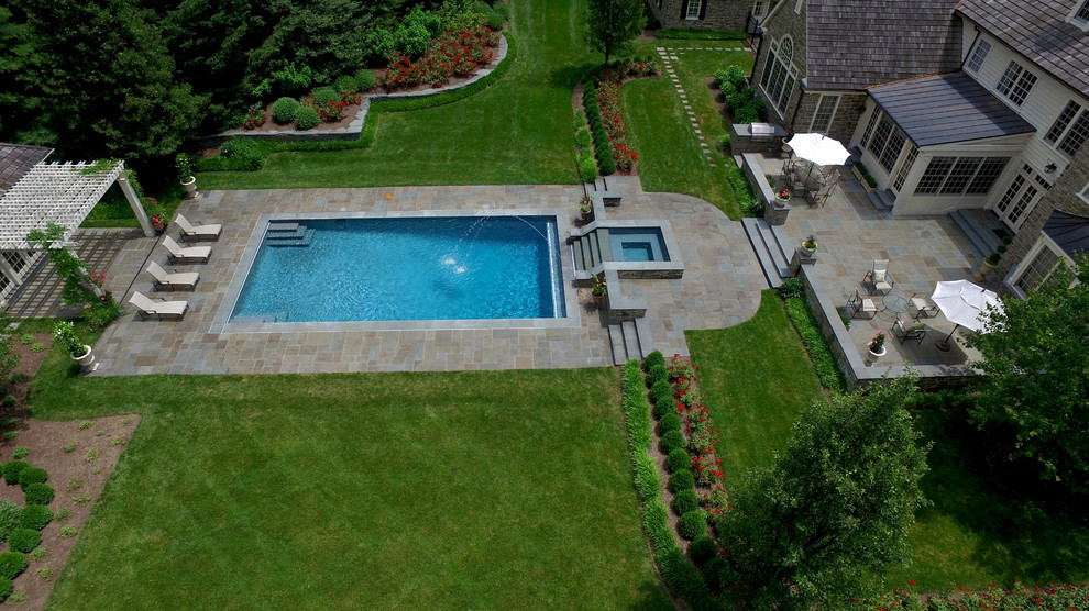 Design ideas for a large traditional backyard rectangular lap pool in Philadelphia with a water feature and natural stone pavers.