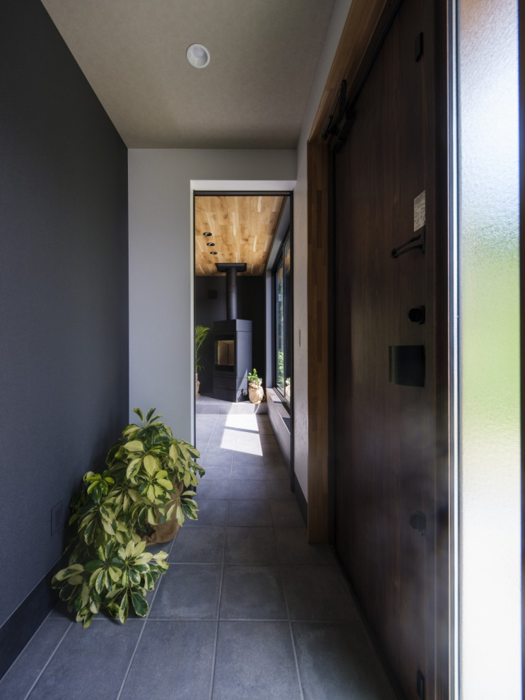 Inspiration pour une entrée minimaliste de taille moyenne avec un couloir, un mur noir, une porte simple, une porte marron, un sol noir, un plafond en papier peint et du papier peint.