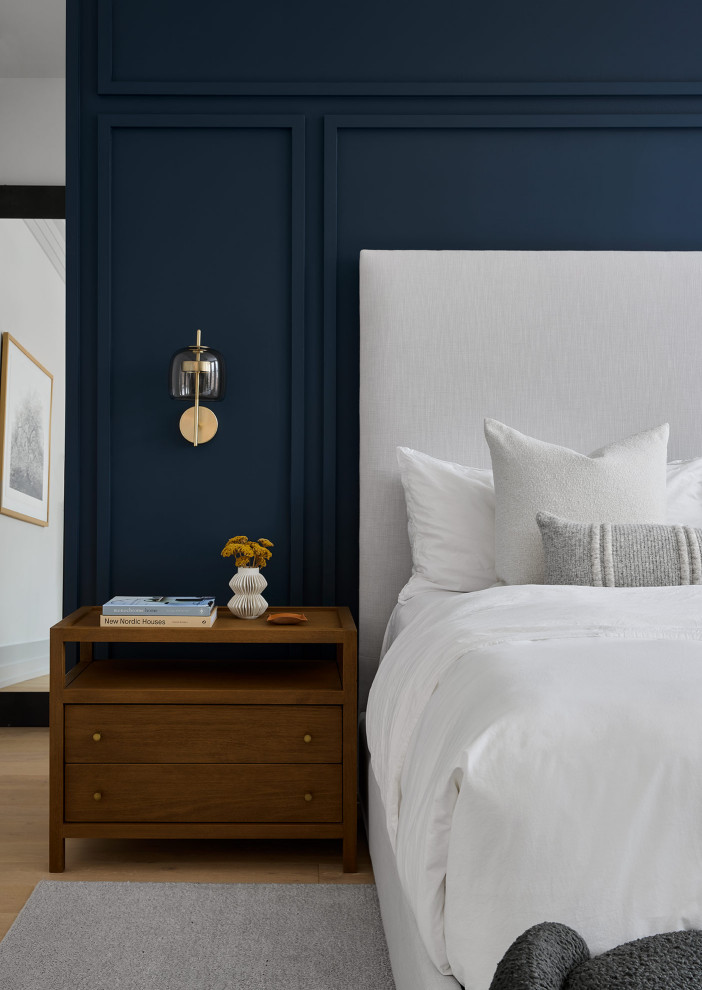 Modern master bedroom in Chicago with blue walls, light hardwood flooring and panelled walls.