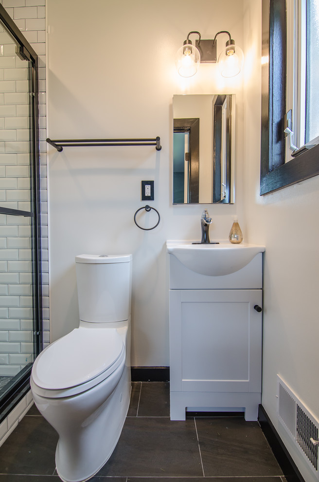Inspiration for a small contemporary master bathroom in DC Metro with shaker cabinets, white cabinets, an alcove shower, a two-piece toilet, black and white tile, ceramic tile, porcelain floors, an integrated sink, solid surface benchtops, black floor, a sliding shower screen and white benchtops.