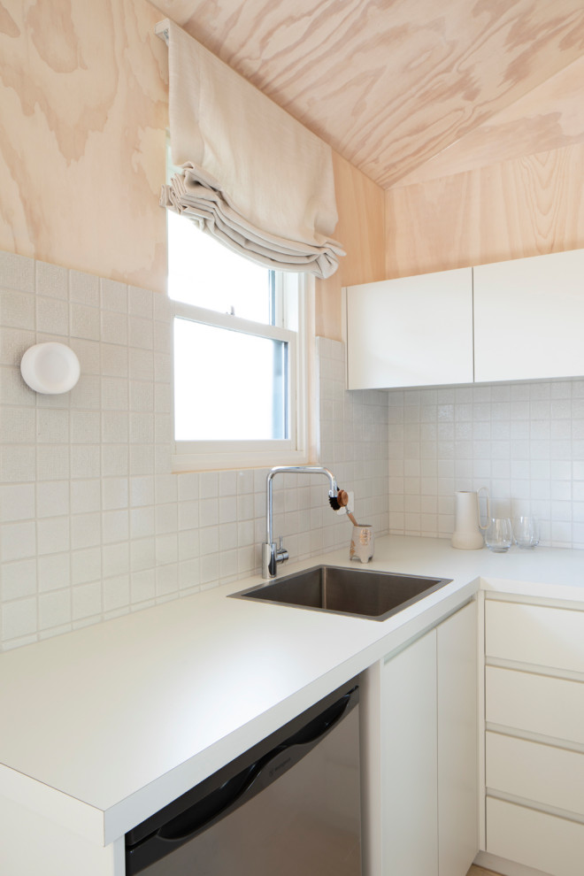 Exempel på ett litet modernt vit vitt kök, med en integrerad diskho, släta luckor, vita skåp, laminatbänkskiva, vitt stänkskydd, stänkskydd i mosaik, rostfria vitvaror, målat trägolv och vitt golv
