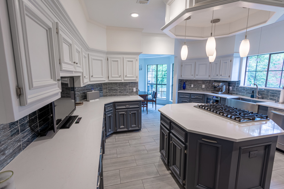 Example of a mid-sized transitional u-shaped ceramic tile and gray floor enclosed kitchen design in Austin with a farmhouse sink, recessed-panel cabinets, white cabinets, quartzite countertops, blue backsplash, glass tile backsplash, stainless steel appliances, an island and white countertops
