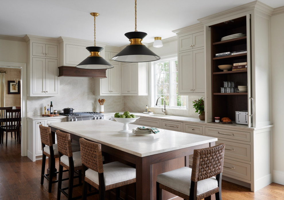 Inspiration for a transitional l-shaped kitchen in Boston with an undermount sink, recessed-panel cabinets, beige cabinets, beige splashback, stone slab splashback, stainless steel appliances, medium hardwood floors, with island, brown floor and beige benchtop.