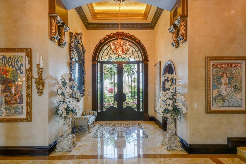 Photo of an expansive mediterranean foyer in Miami with yellow walls, marble floors, a double front door, a glass front door and multi-coloured floor.