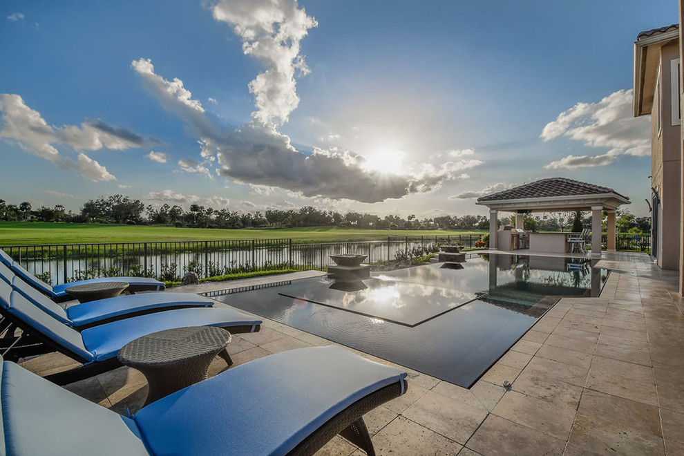 Large contemporary backyard custom-shaped infinity pool in Miami with a hot tub and natural stone pavers.