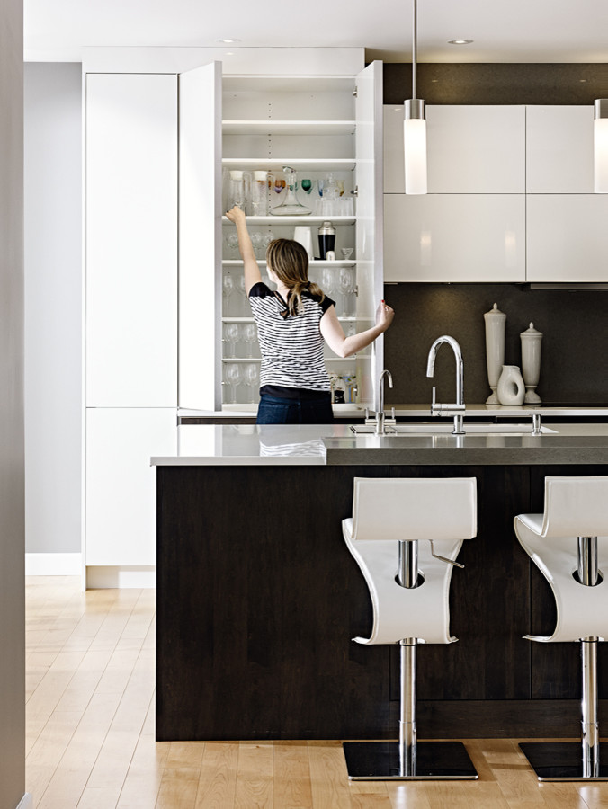 Example of a large minimalist l-shaped light wood floor eat-in kitchen design with an undermount sink, flat-panel cabinets, white cabinets, quartz countertops, stone slab backsplash, stainless steel appliances and an island