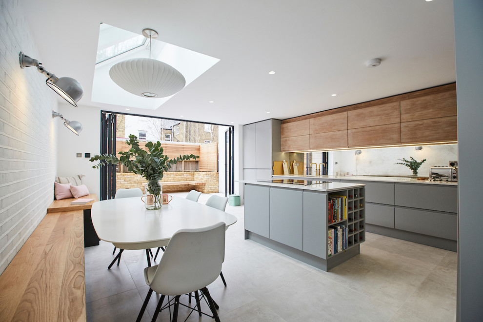Photo of a mid-sized contemporary open plan kitchen in Sussex with an integrated sink, solid surface benchtops, mirror splashback, panelled appliances, ceramic floors, with island, grey floor, white benchtop, flat-panel cabinets and grey cabinets.