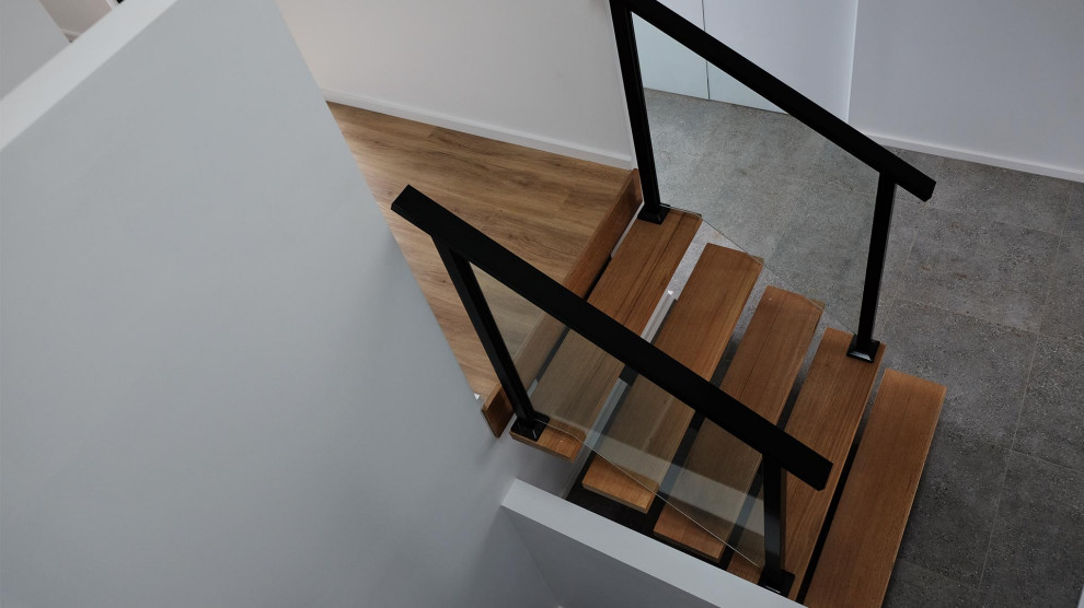 Medium sized contemporary wood glass railing staircase in Geelong with wood risers.