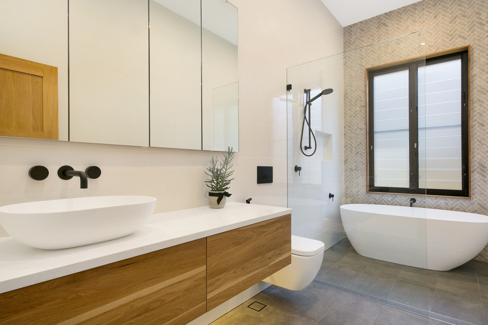 Large contemporary master wet room bathroom in Sydney with a freestanding tub, ceramic floors, an open shower, a floating vanity, flat-panel cabinets, medium wood cabinets, a wall-mount toilet, gray tile, mosaic tile, a vessel sink, grey floor, white benchtops, a niche and a single vanity.