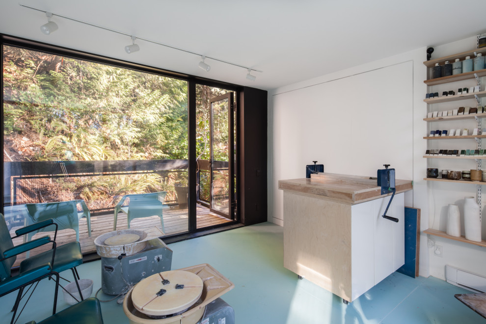 Ejemplo de estudio contemporáneo con paredes blancas, suelo de cemento y suelo azul