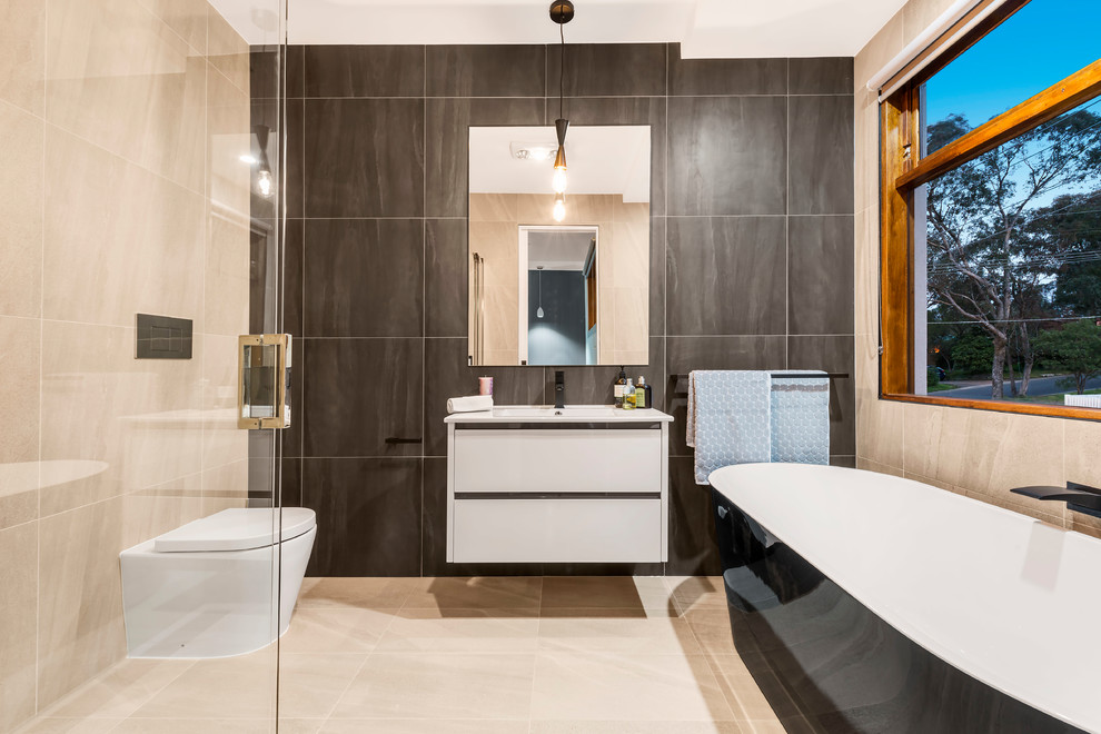 Inspiration for a contemporary 3/4 bathroom in Melbourne with flat-panel cabinets, white cabinets, a freestanding tub, a corner shower, a one-piece toilet, beige tile, gray tile, beige floor, a hinged shower door and white benchtops.
