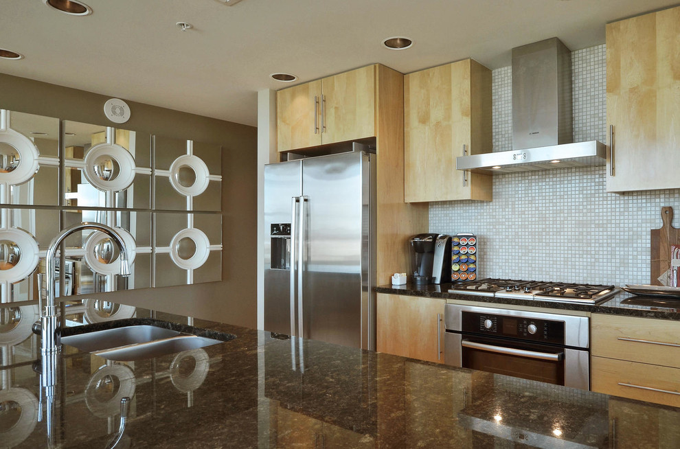 Inspiration for a small transitional galley light wood floor open concept kitchen remodel in Austin with a double-bowl sink, flat-panel cabinets, light wood cabinets, granite countertops, beige backsplash, mosaic tile backsplash, stainless steel appliances and an island