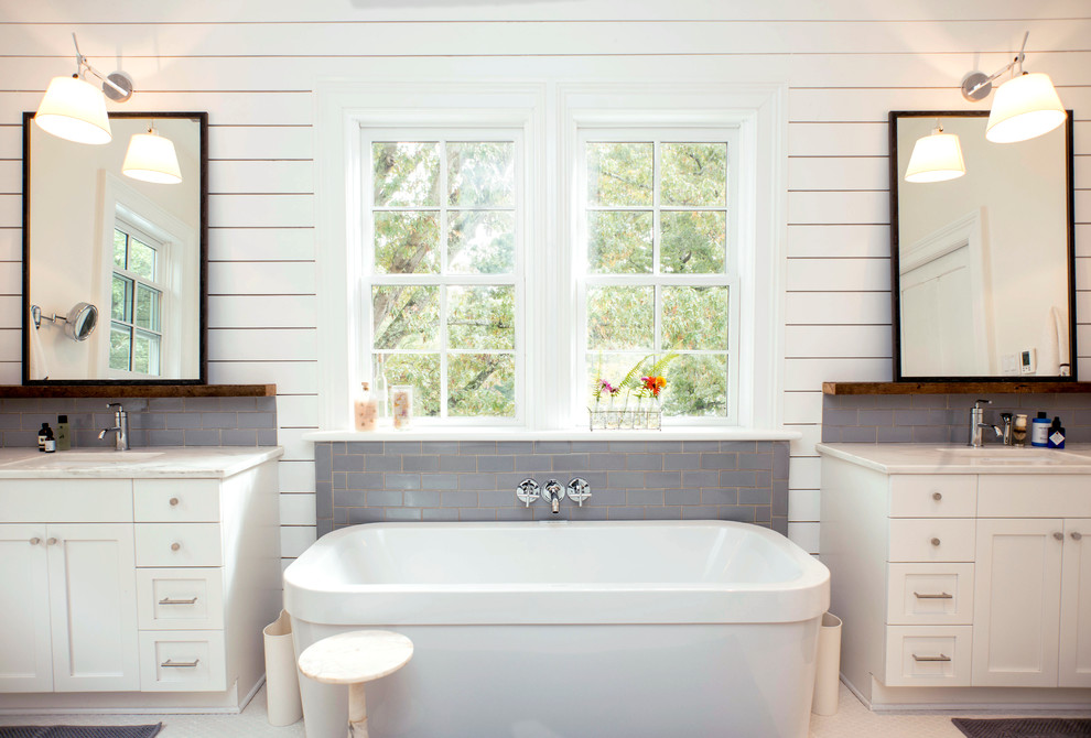 Country bathroom in Raleigh with a freestanding tub, shaker cabinets, white cabinets, gray tile and white walls.