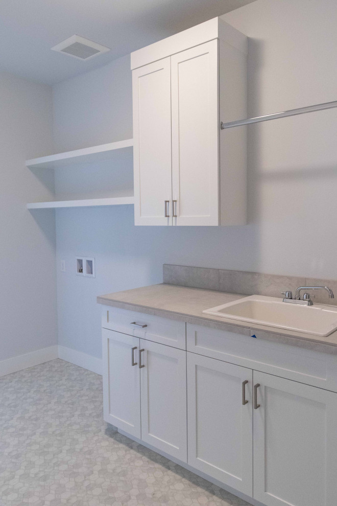 Inspiration for a mid-sized contemporary galley dedicated laundry room in Other with a drop-in sink, shaker cabinets, white cabinets, tile benchtops, beige splashback, ceramic splashback, white walls, vinyl floors, a side-by-side washer and dryer, beige floor and beige benchtop.
