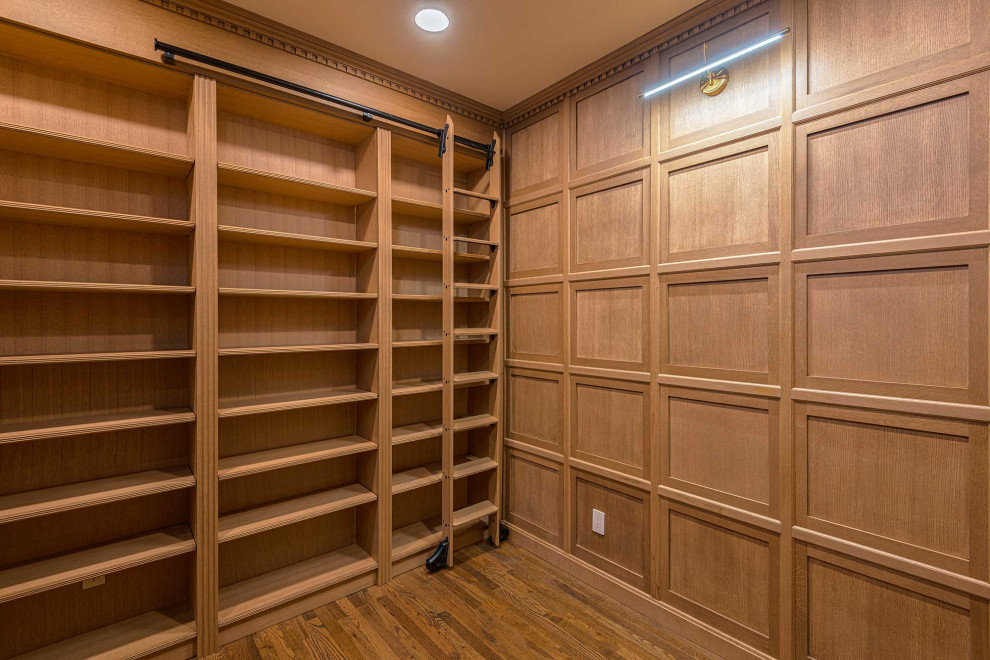 Example of a small classic built-in desk dark wood floor, brown floor and wainscoting home office library design in New York