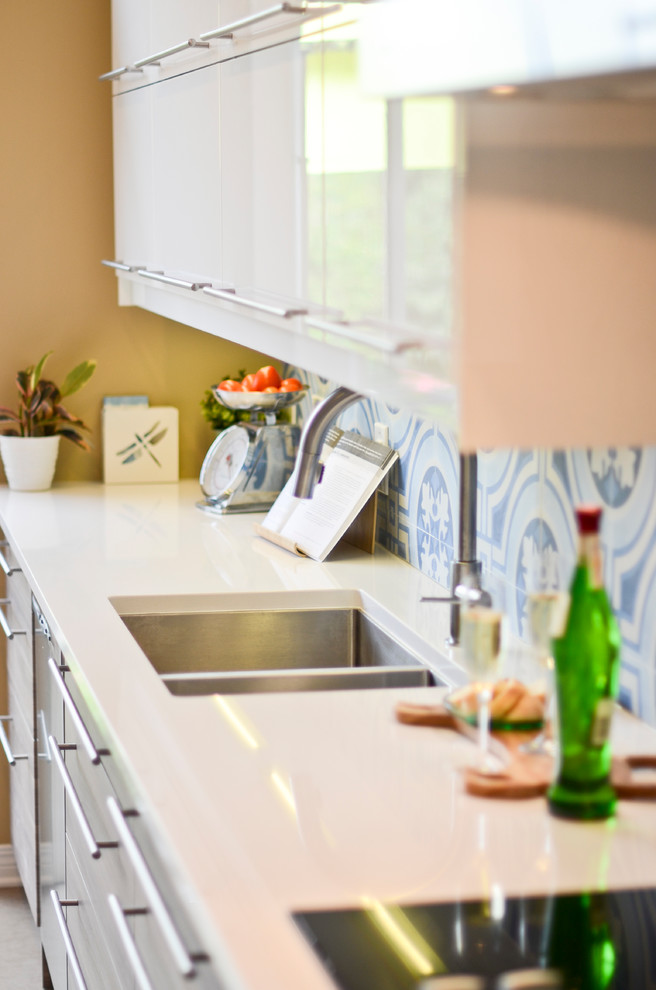 Mid-sized minimalist l-shaped cork floor eat-in kitchen photo in Ottawa with an undermount sink, flat-panel cabinets, white cabinets, quartzite countertops, blue backsplash, porcelain backsplash, stainless steel appliances and an island