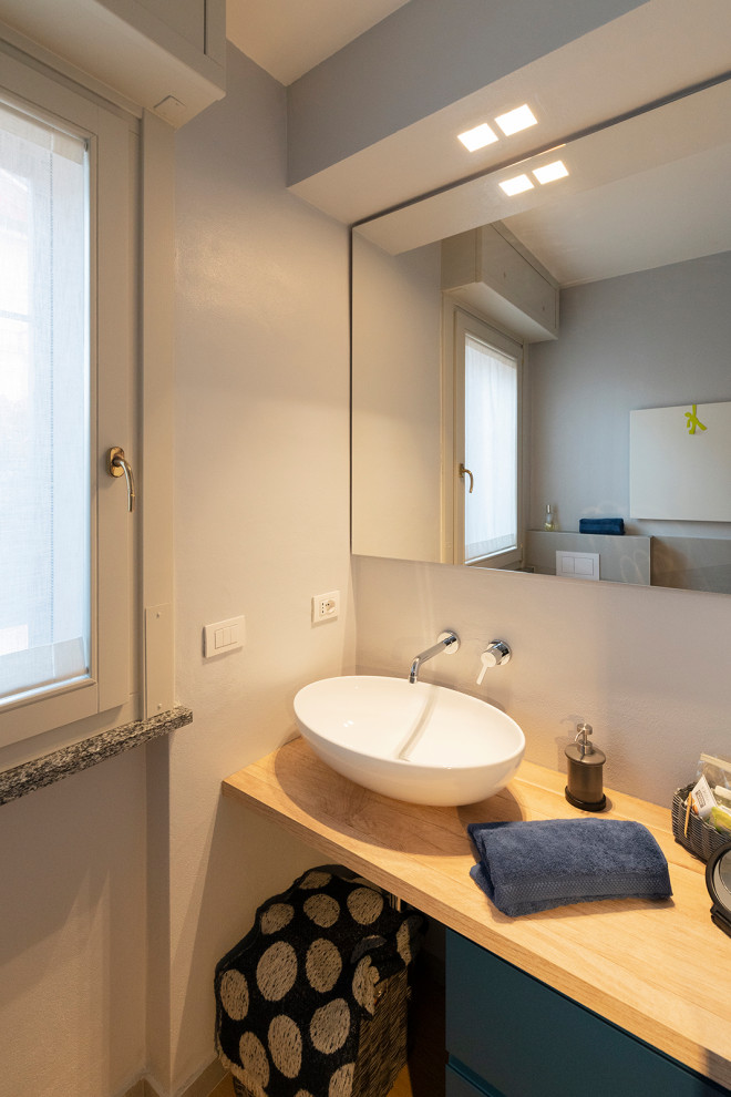 Cette image montre une petite salle de bain minimaliste avec un carrelage gris, des carreaux de miroir, un mur gris, sol en stratifié, une vasque, un plan de toilette en bois, un sol marron, une cabine de douche à porte coulissante, un plan de toilette marron, meuble simple vasque et meuble-lavabo suspendu.