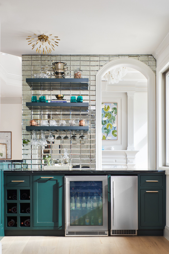 Design ideas for a mid-sized transitional l-shaped wet bar in Austin with green cabinets, mirror splashback, medium hardwood floors, black benchtop and beaded inset cabinets.