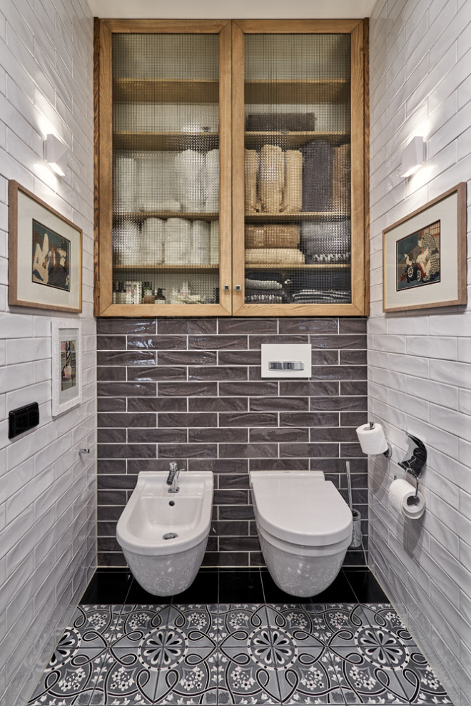 Inspiration for a large bathroom in Saint Petersburg with glass-front cabinets, light wood cabinets, a wall-mount toilet, gray tile, subway tile, grey walls, ceramic floors, grey floor and a niche.