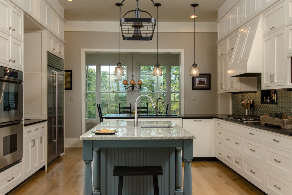 This is an example of a large country u-shaped eat-in kitchen in DC Metro with a farmhouse sink, recessed-panel cabinets, white cabinets, granite benchtops, grey splashback, metal splashback, stainless steel appliances, light hardwood floors and with island.