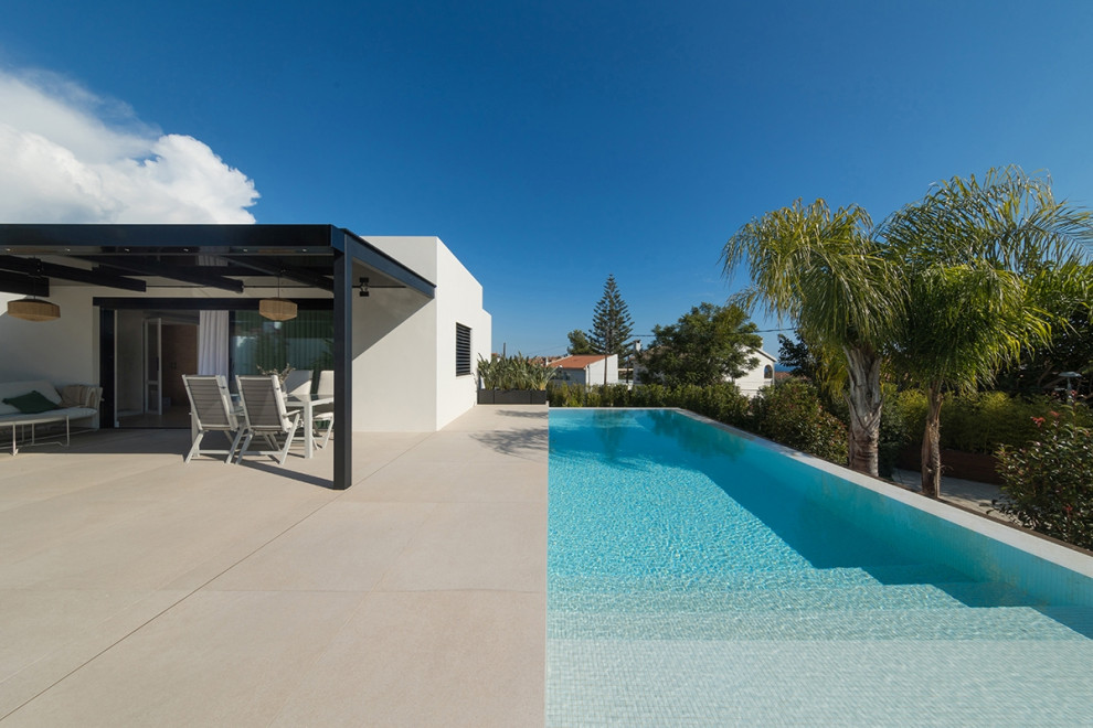 На фото: большой прямоугольный бассейн на переднем дворе в средиземноморском стиле с покрытием из плитки с