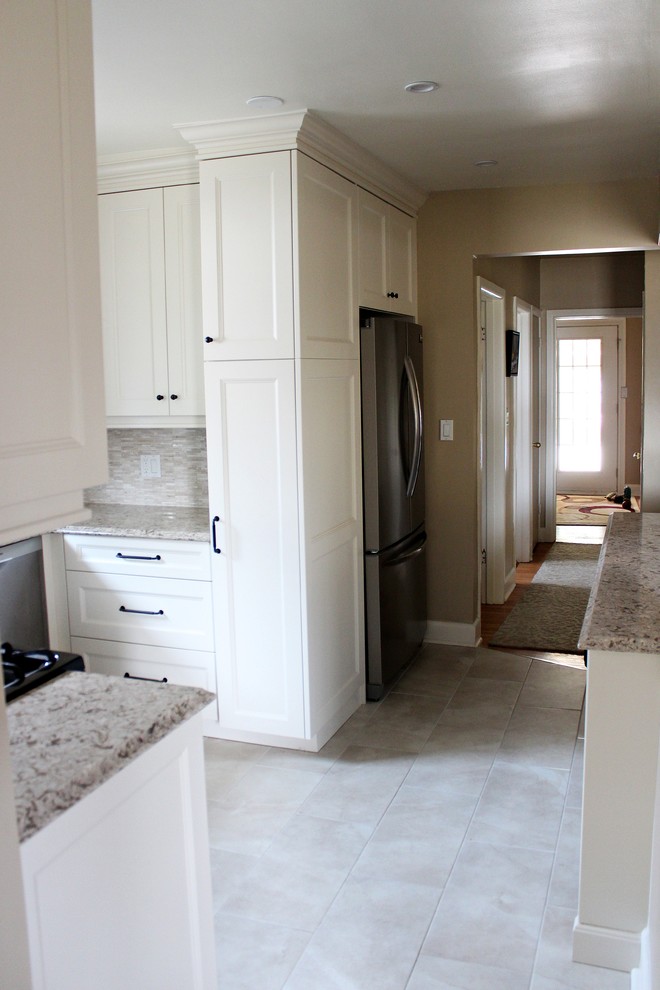 This is an example of a small transitional u-shaped separate kitchen in Toronto with an undermount sink, shaker cabinets, beige cabinets, quartz benchtops, beige splashback, stone tile splashback, stainless steel appliances, porcelain floors and a peninsula.