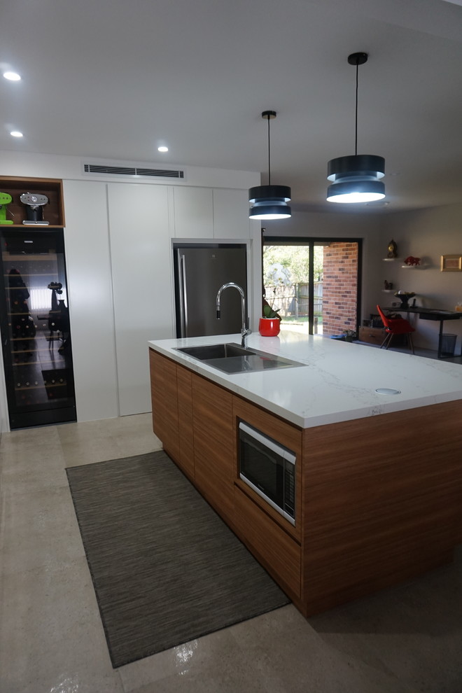 This is an example of a mid-sized contemporary l-shaped eat-in kitchen in Sydney with a drop-in sink, white cabinets, quartz benchtops, white splashback, porcelain splashback, stainless steel appliances, ceramic floors and with island.