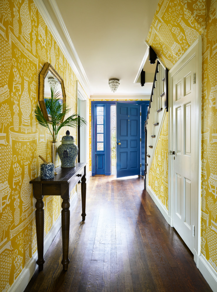 Foto di un grande corridoio tradizionale con pareti gialle, pavimento in legno massello medio, una porta singola, una porta blu, pavimento marrone e carta da parati