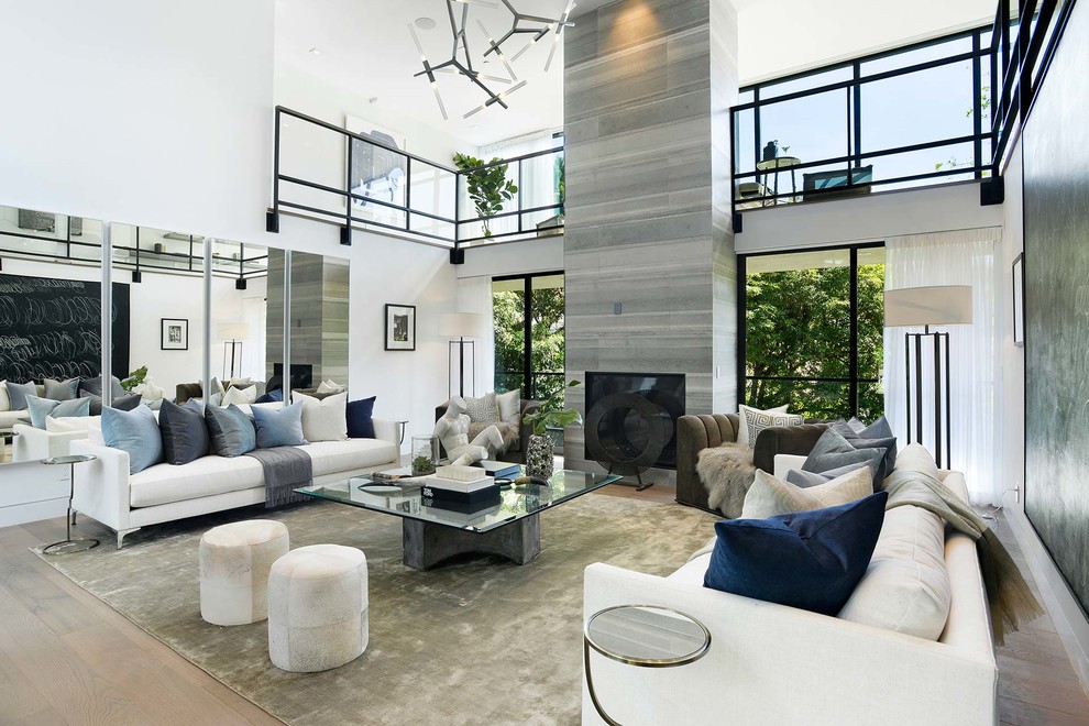 Inspiration for a contemporary living room in Los Angeles with white walls, medium hardwood floors, a standard fireplace, a tile fireplace surround and brown floor.
