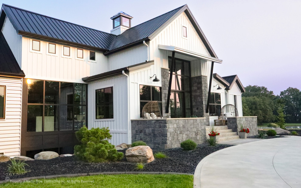 Inspiration for a large cottage white two-story metal and board and batten house exterior remodel in Other with a metal roof and a black roof