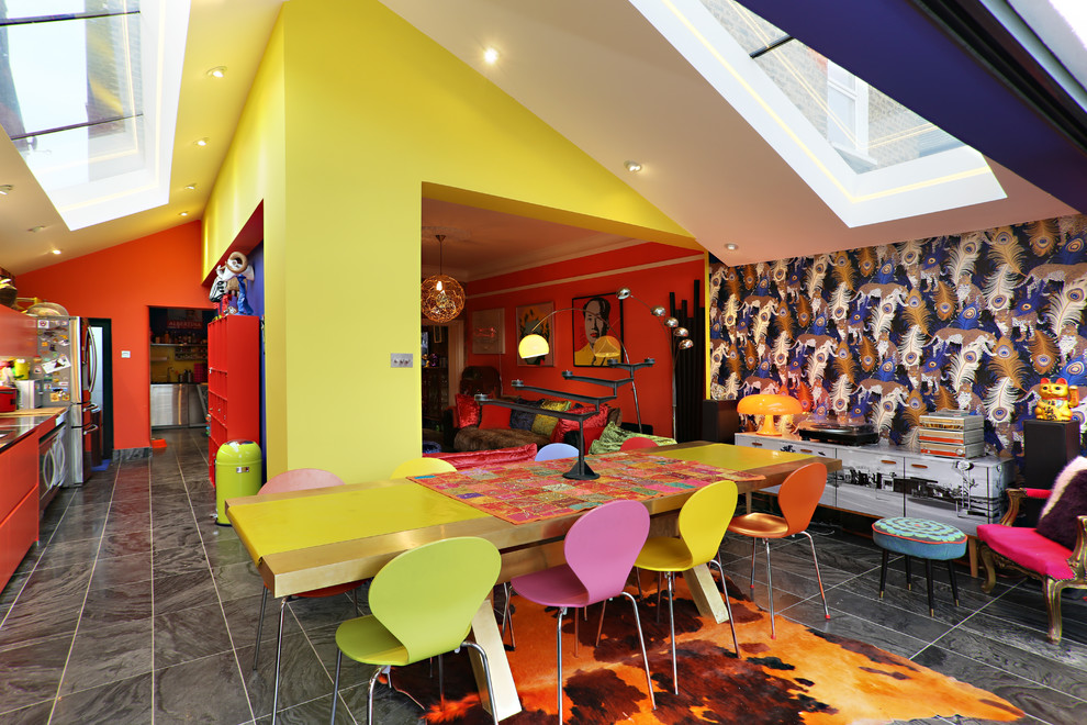 This is an example of a large eclectic open plan dining in London with yellow walls and grey floor.