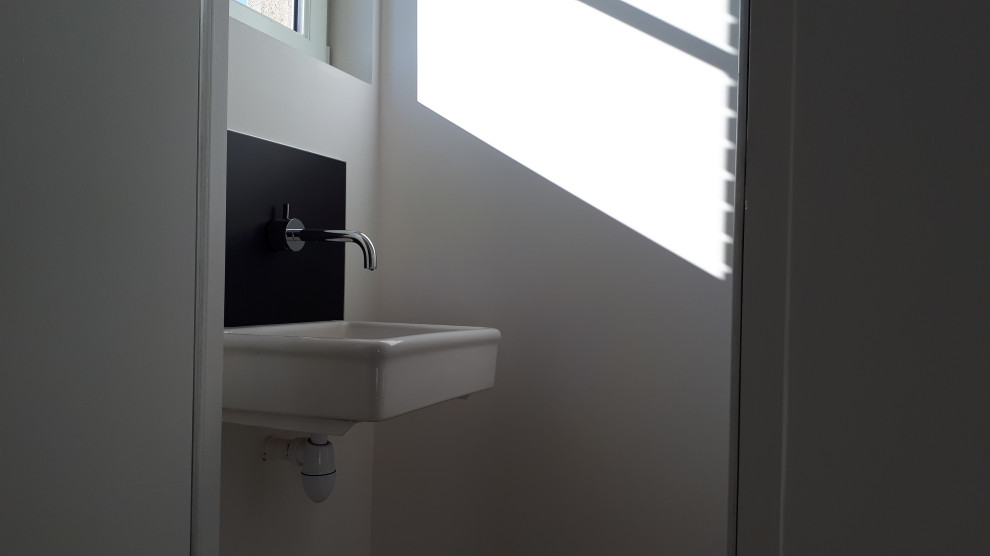 Источник вдохновения для домашнего уюта: туалет в стиле модернизм с инсталляцией, белыми стенами, подвесной раковиной и бежевым полом