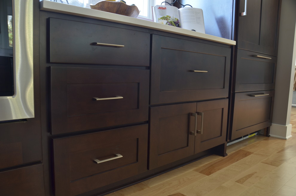Example of a large transitional u-shaped light wood floor home design design with an undermount sink, shaker cabinets, dark wood cabinets, quartz countertops, stainless steel appliances and an island