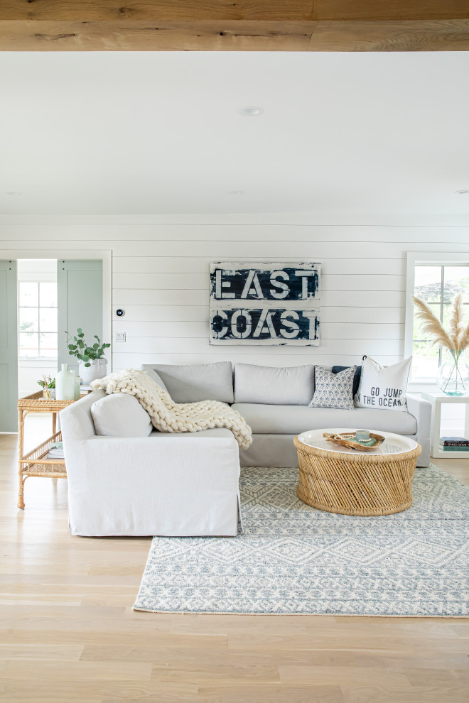 Example of a large beach style open concept light wood floor, brown floor, exposed beam and shiplap wall living room design in Other with white walls, a standard fireplace, a shiplap fireplace and a wall-mounted tv