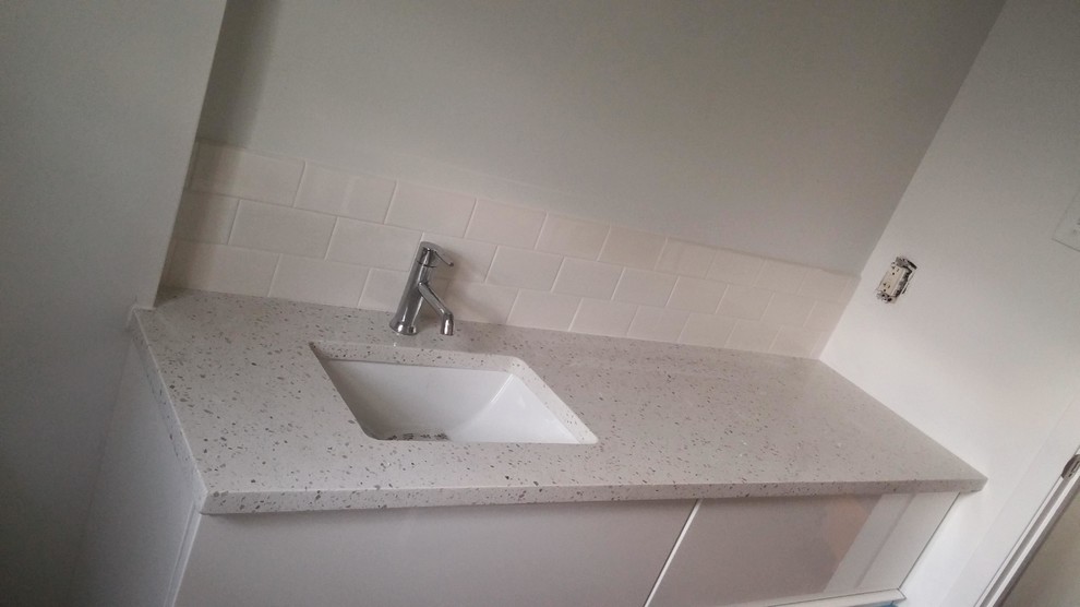 Photo of a mid-sized scandinavian 3/4 bathroom in Austin with flat-panel cabinets, white cabinets, an alcove shower, a one-piece toilet, white tile, subway tile, white walls, an undermount sink and terrazzo benchtops.