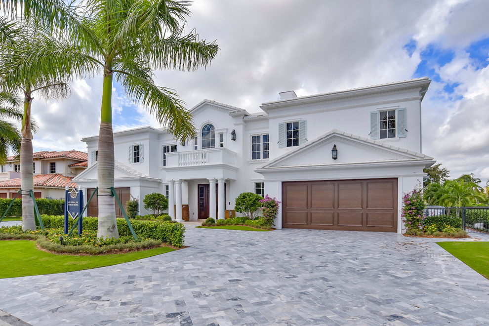 This is an example of a large transitional two-storey stucco white exterior in Miami with a hip roof.