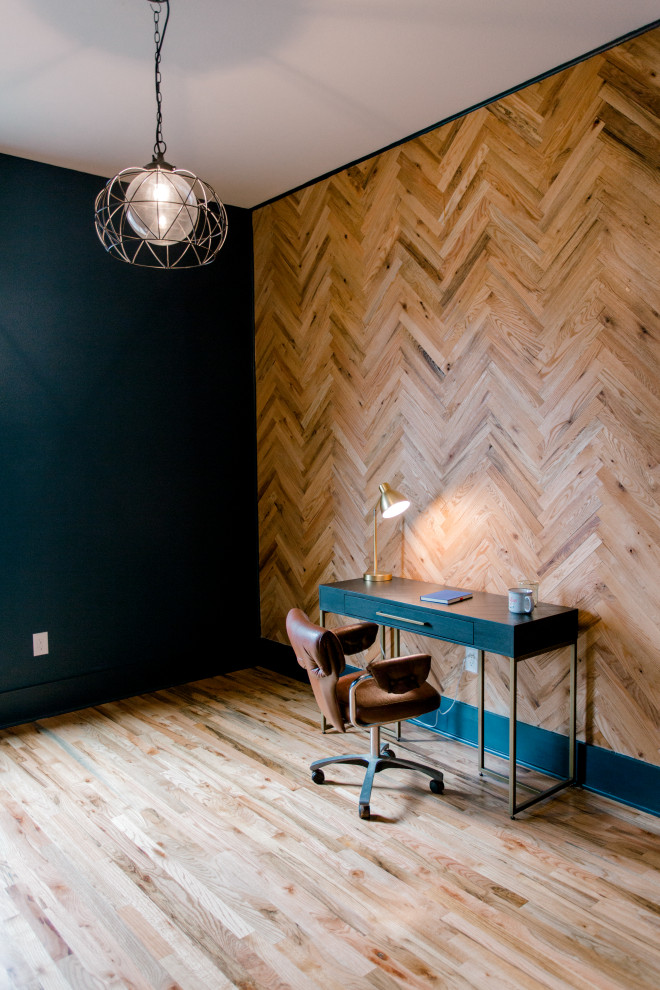 Inredning av ett retro mellanstort arbetsrum, med svarta väggar, ljust trägolv, ett fristående skrivbord och brunt golv