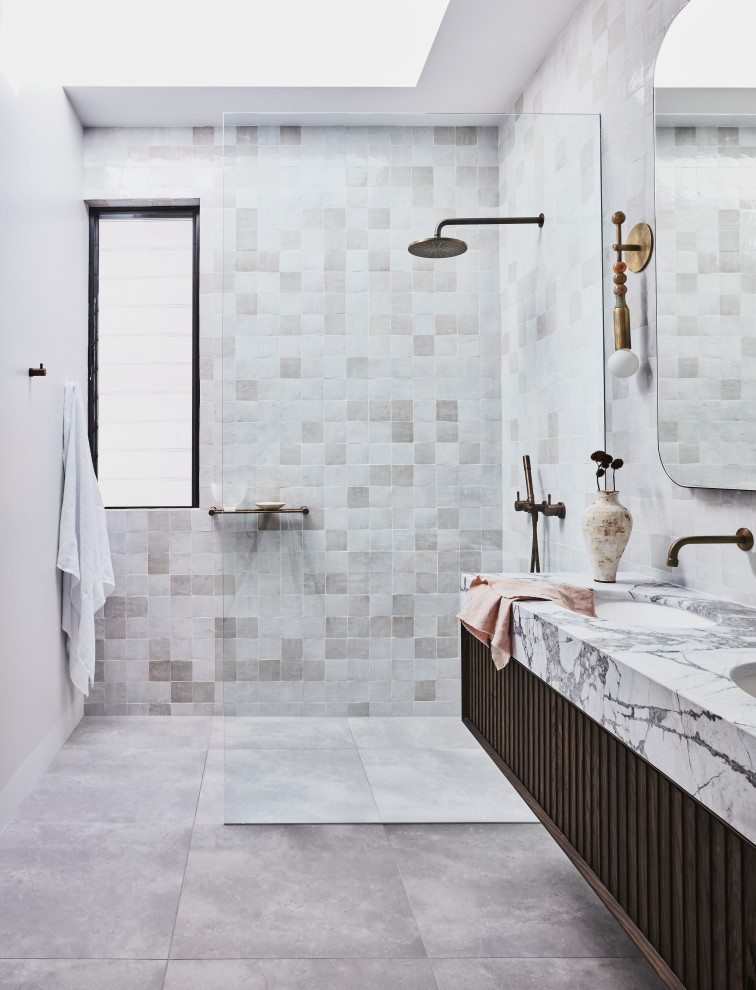 Foto på ett stort funkis grå en-suite badrum, med bruna skåp, ett fristående badkar, en öppen dusch, beige kakel, porslinskakel, vita väggar, klinkergolv i keramik, ett integrerad handfat, marmorbänkskiva, flerfärgat golv, med dusch som är öppen och släta luckor