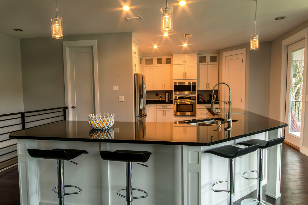 Eat-in kitchen - large l-shaped eat-in kitchen idea with an undermount sink, shaker cabinets, white cabinets, granite countertops, an island and black countertops