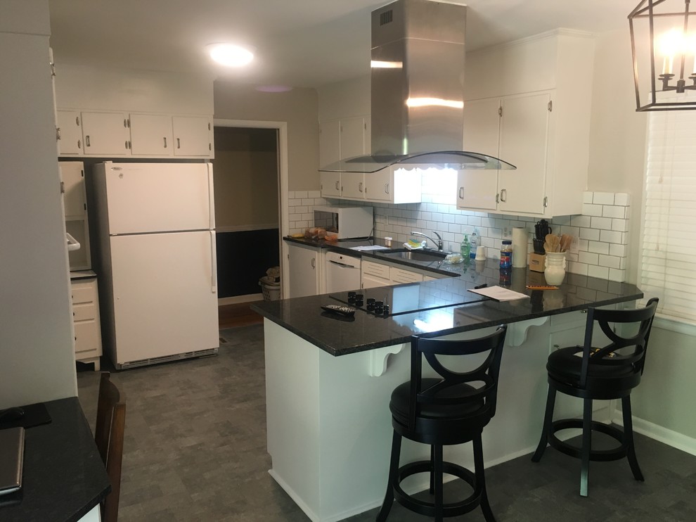 This is an example of a mid-sized contemporary u-shaped eat-in kitchen in Birmingham with an undermount sink, flat-panel cabinets, white cabinets, white splashback, subway tile splashback, a peninsula, granite benchtops, white appliances, laminate floors, grey floor and black benchtop.