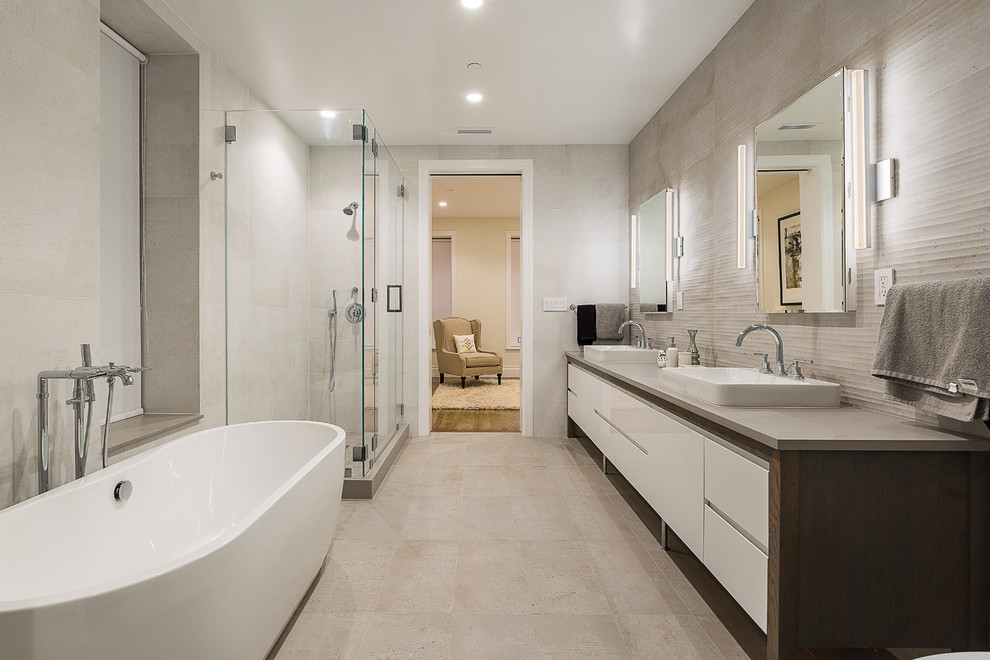 Design ideas for a contemporary master bathroom in New York with flat-panel cabinets, white cabinets, a freestanding tub, beige tile, beige walls, a vessel sink, beige floor and a hinged shower door.