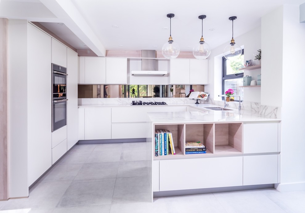 Design ideas for a contemporary u-shaped kitchen in Berkshire with flat-panel cabinets, mirror splashback, black appliances, grey floor, a double-bowl sink, white cabinets, a peninsula and multi-coloured benchtop.