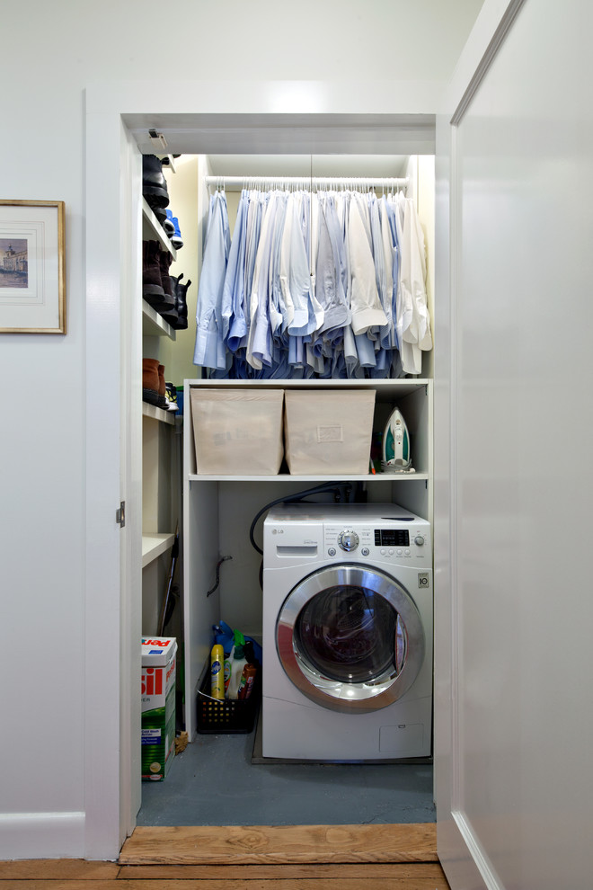 This is an example of a small transitional l-shaped utility room in New York with open cabinets, white cabinets, white walls, vinyl floors and a stacked washer and dryer.