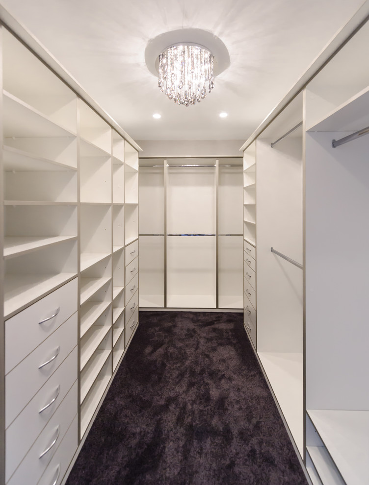 This is an example of an expansive modern women's walk-in wardrobe in Melbourne with open cabinets, white cabinets and carpet.