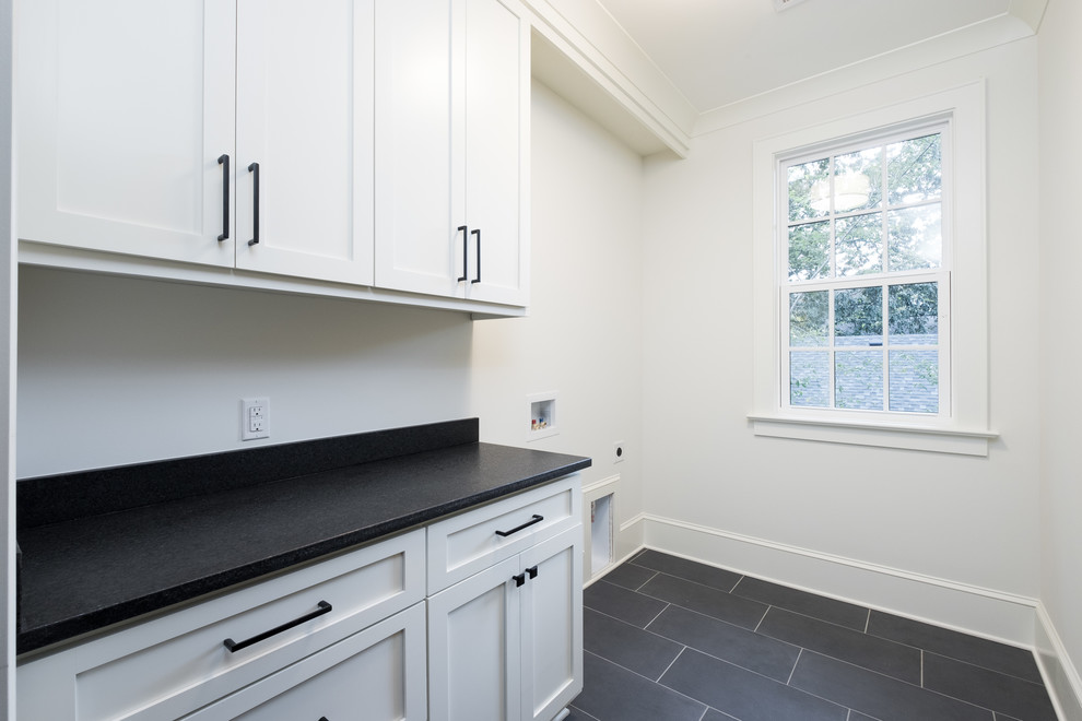 This is an example of a mid-sized traditional single-wall dedicated laundry room in Charlotte with granite benchtops, white walls, a side-by-side washer and dryer and black benchtop.