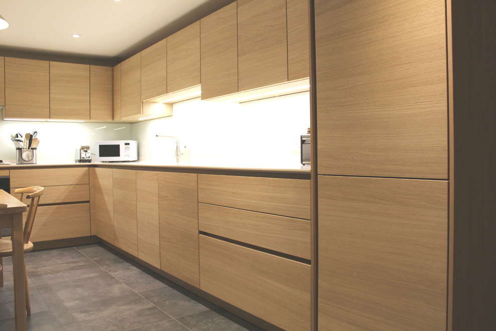 Contemporary l-shaped eat-in kitchen in Wiltshire with an integrated sink, flat-panel cabinets, light wood cabinets, glass sheet splashback, panelled appliances and no island.