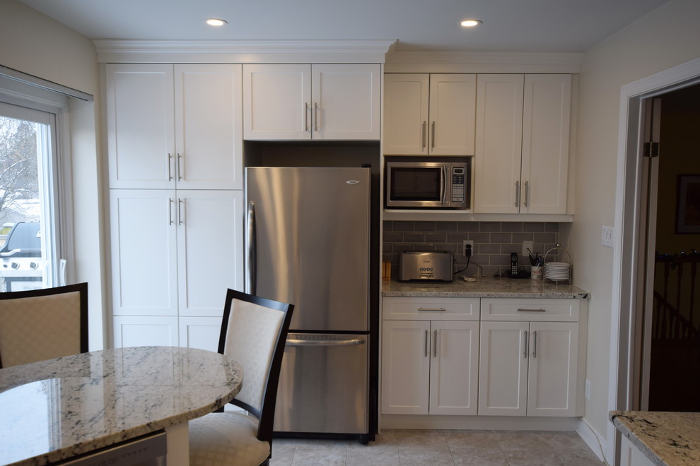 Mid-sized transitional u-shaped ceramic tile enclosed kitchen photo in Ottawa with an undermount sink, shaker cabinets, white cabinets, granite countertops, gray backsplash, glass tile backsplash, stainless steel appliances and a peninsula